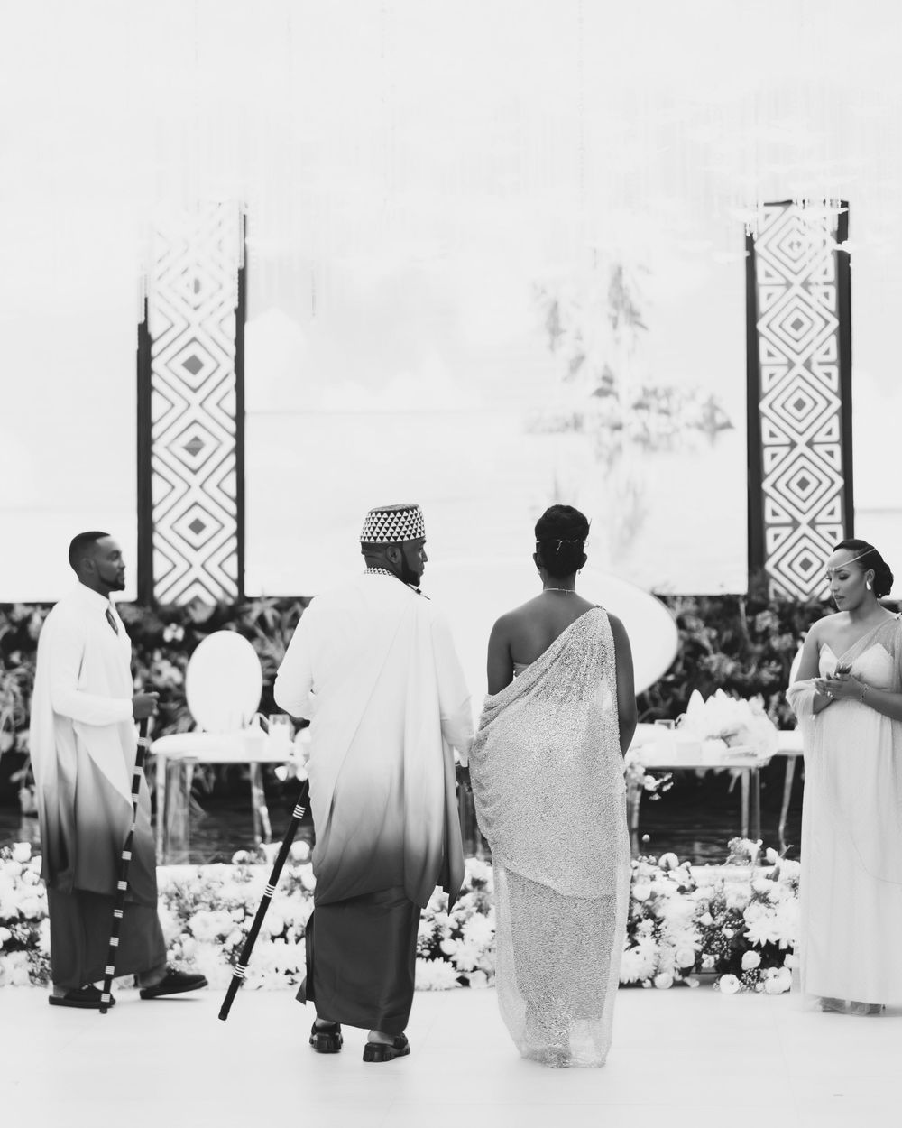 A vintage black and white photograph showing people viewing tall decorative pillars or monuments with geometric patterns.