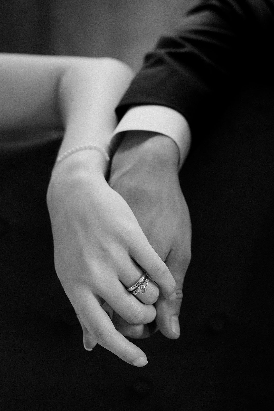 Black and white detail shot of hands showing wedding ring.