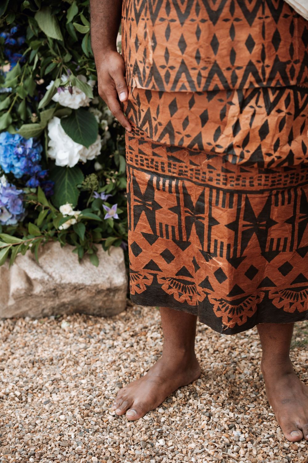 Traditional patterned dress and bare feet against blue hydrangeas and white flowers at aswarby rectory