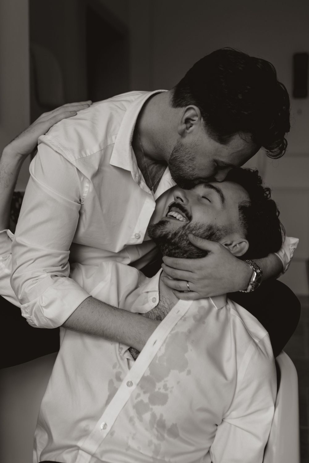 An intimate black and white moment between two people sharing laughter and embrace.