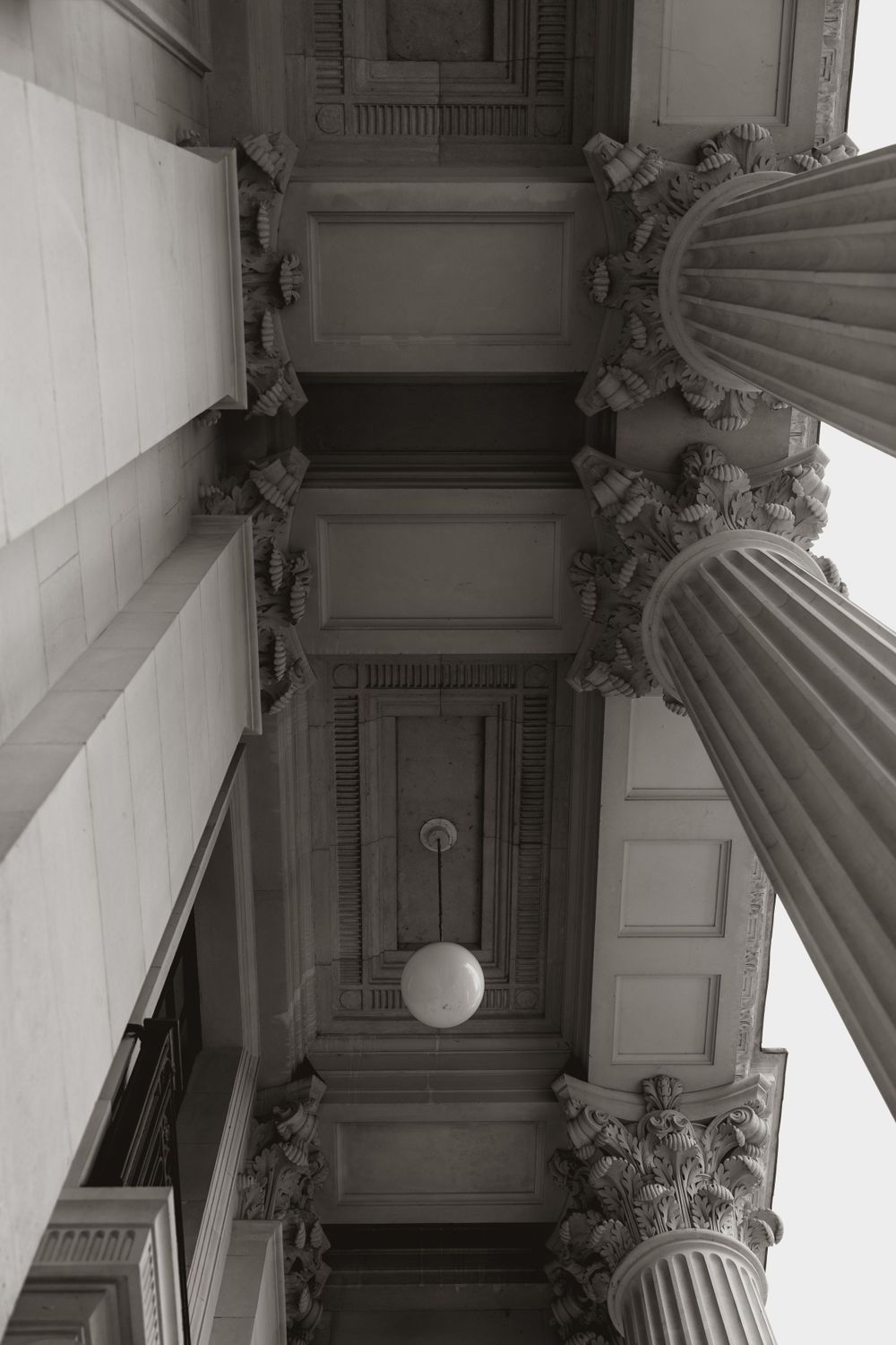 Architectural detail shot looking up at classical columns and ornate ceiling moldings in black and white at Marylebone town hall