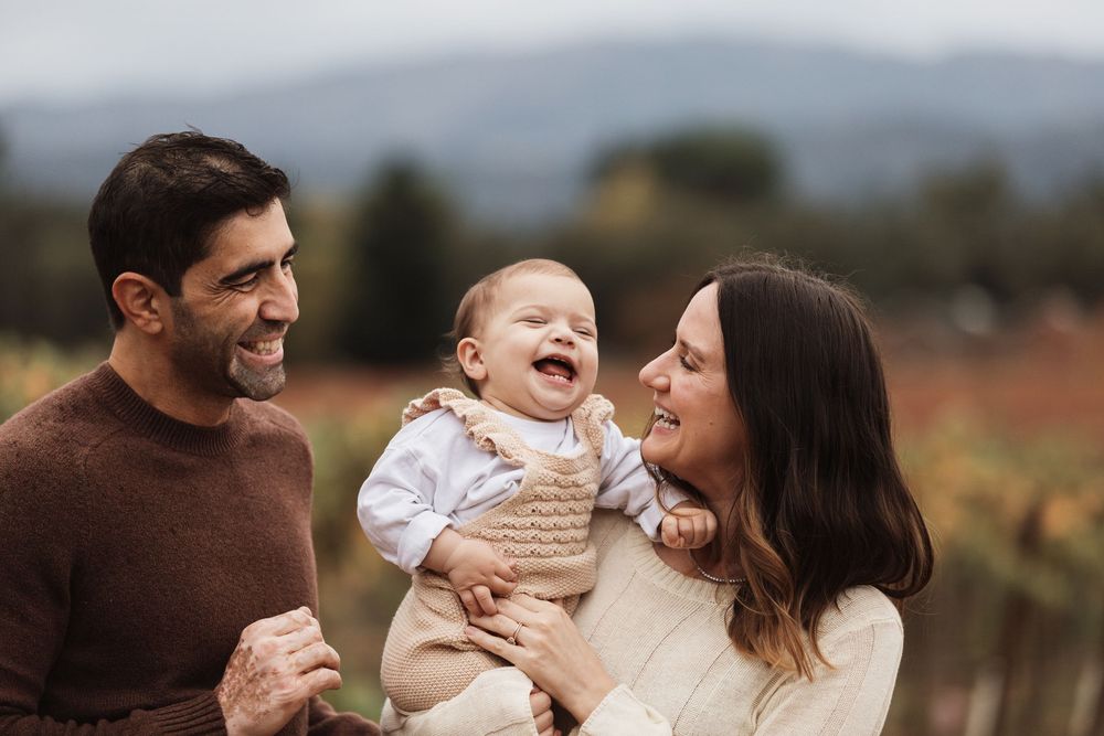 A joyful family shares a laugh together outdoors against an autumn landscape background.