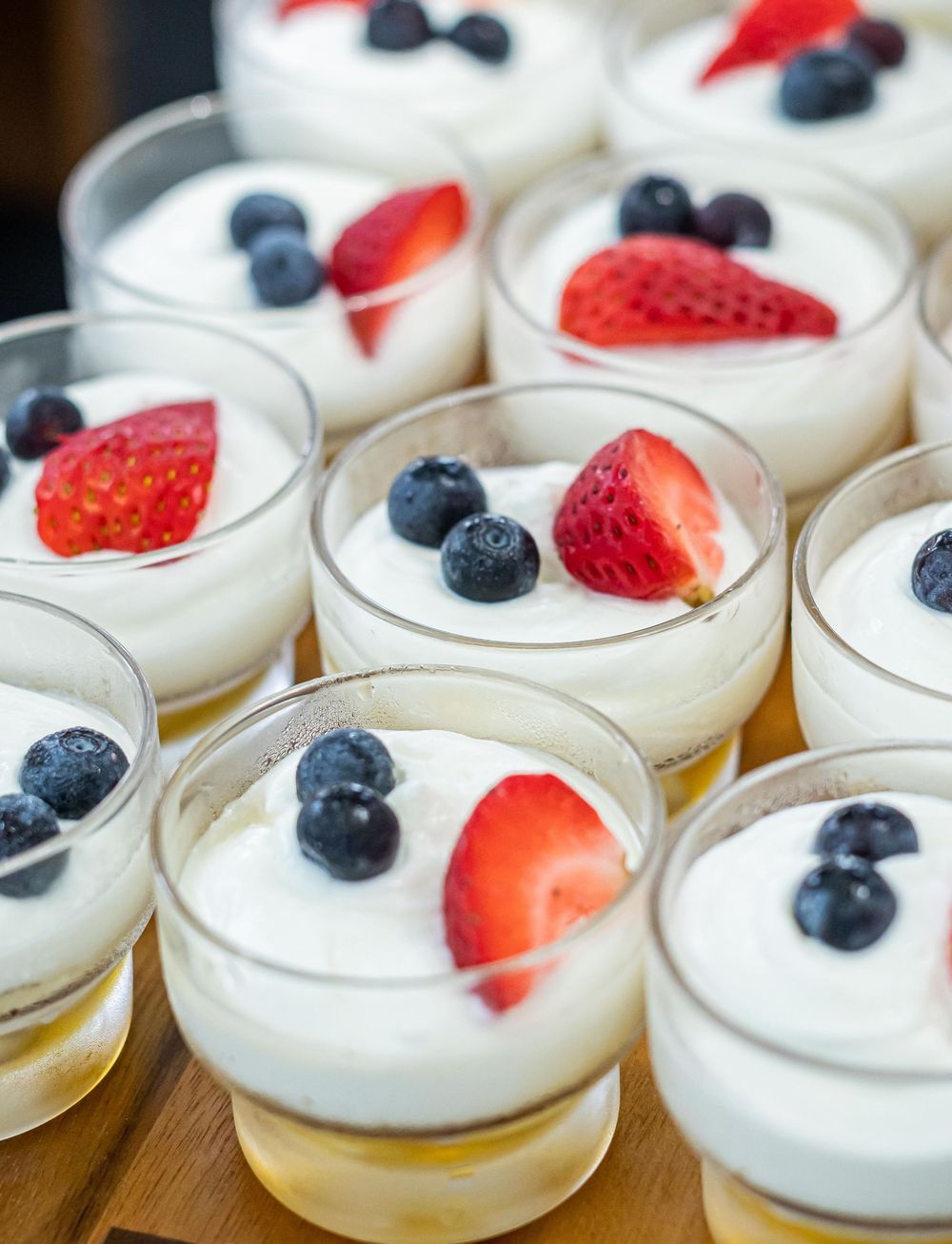 Individual dessert cups filled with creamy mousse, topped with fresh blueberries and strawberry slices.