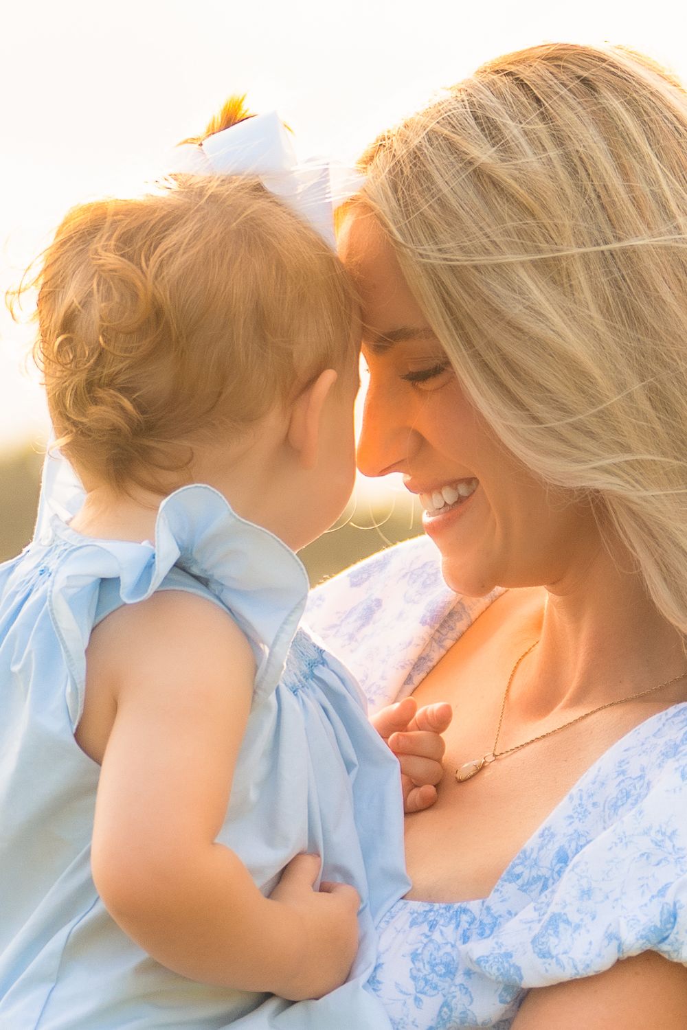A tender moment between parent and child wearing blue clothing in warm sunset lighting.