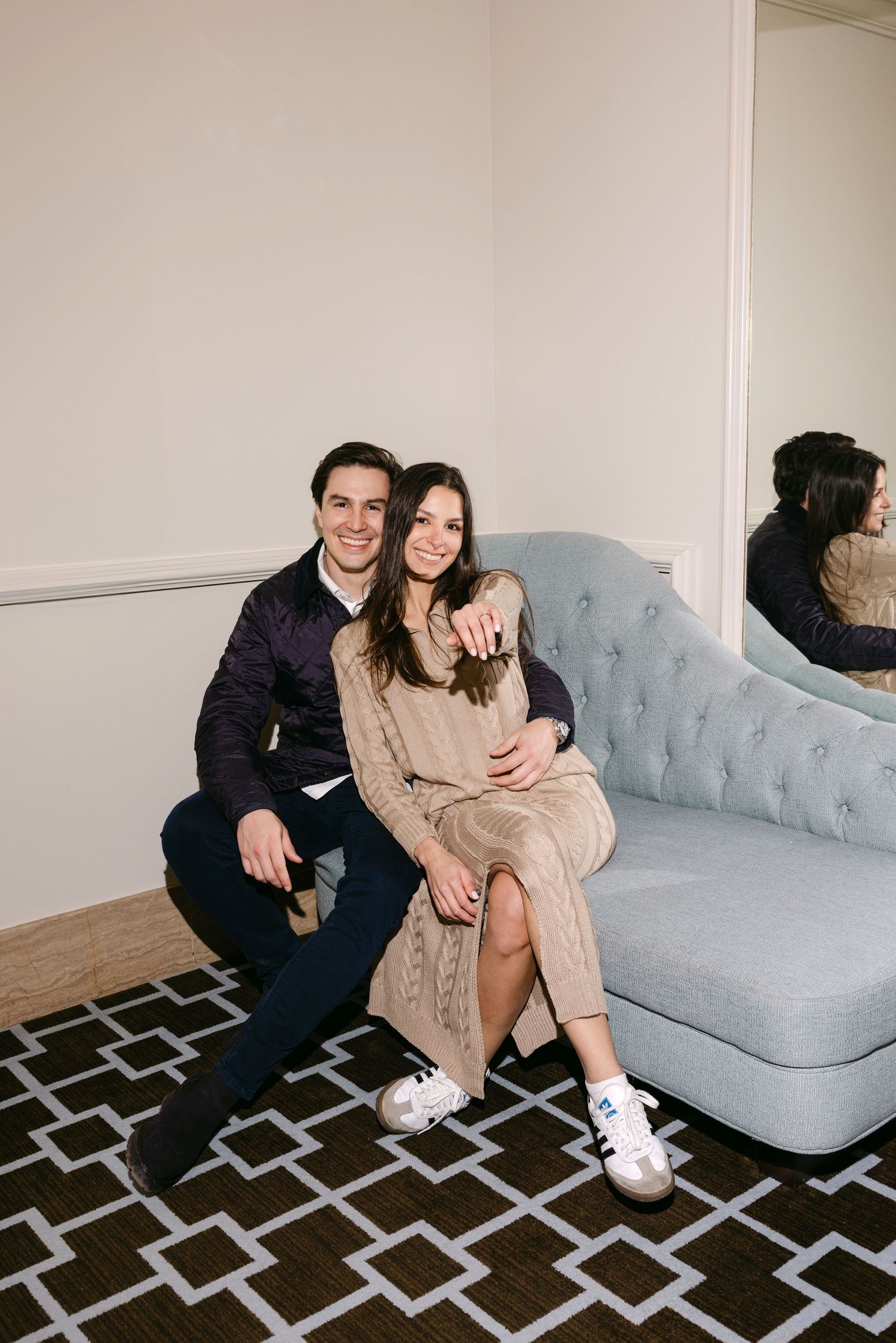 A happy couple shares a candid moment of laughter while wearing winter coats outdoors.
