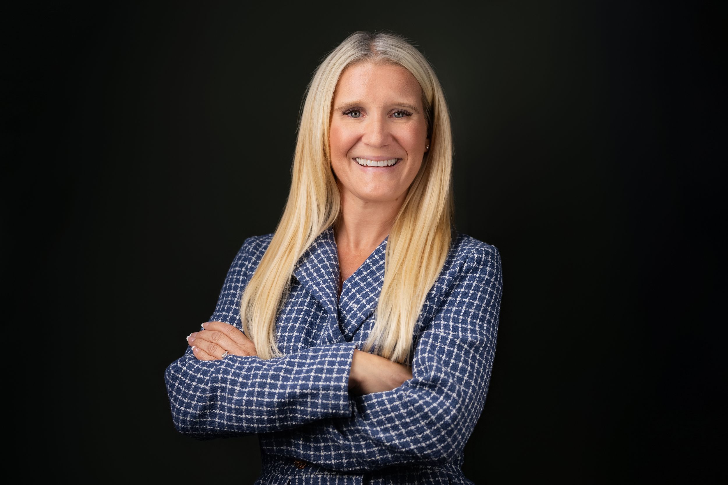 Professional studio portrait of someone wearing a blue checkered button-down shirt with crossed arms.