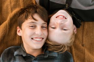A couple shares a tender moment while lying on a wooden floor with warm lighting and rustic ambiance.