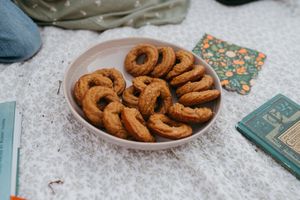 A plate of fresh cinnamon sugar churros arranged in a circular pattern on a white surface with books nearby.