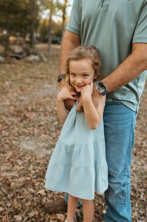 A family shares tender moments together on a stone pathway surrounded by greenery and trees.