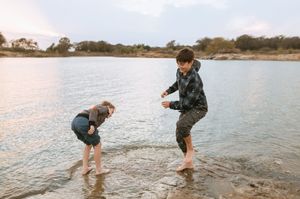 People enjoying a playful moment at the water's edge on a sunny day at a lake or reservoir.