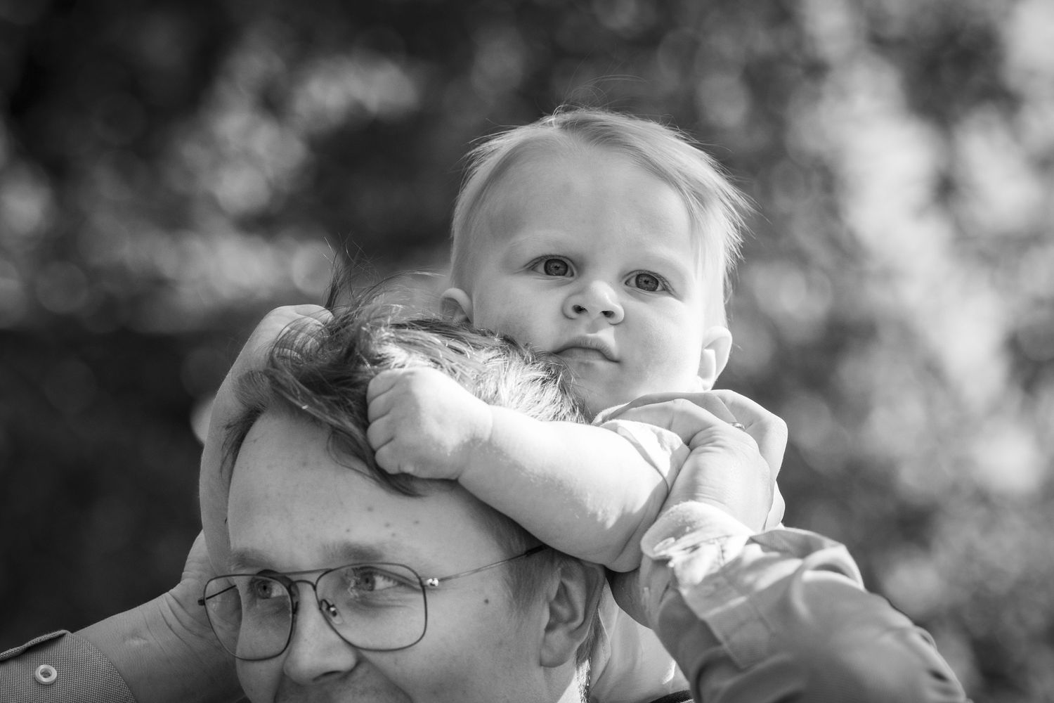 Mustavalkoinen kuva isänsä olkapäillä istuvasta vuosikkaasta.