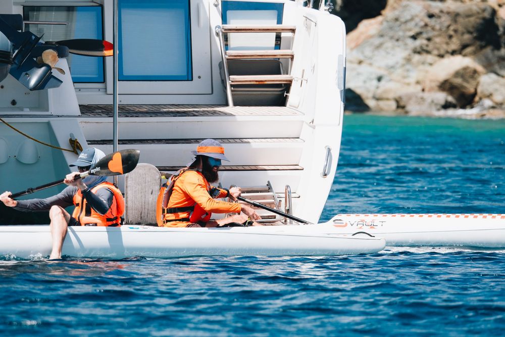 People relax on a yacht deck while sailing in crystal blue waters on a sunny summer day.