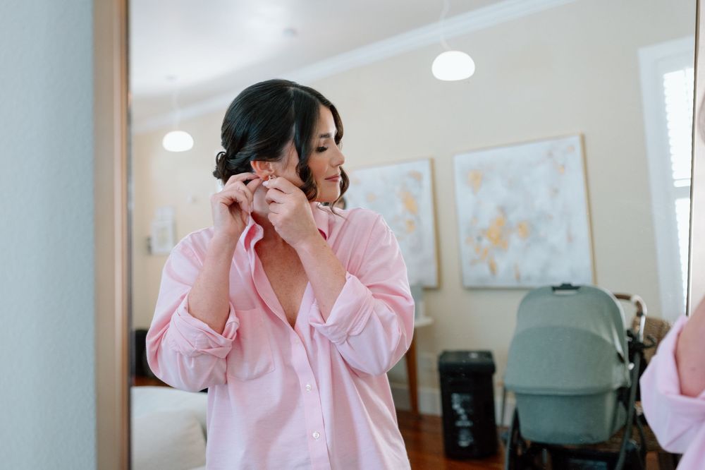 Bride putting on earrings in Airbnb before downtown Pensacola wedding