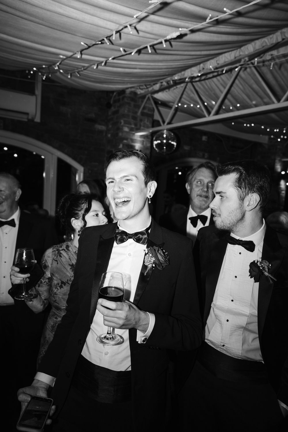 A black and white photo series showing people in formal attire enjoying drinks and laughing at an elegant party.