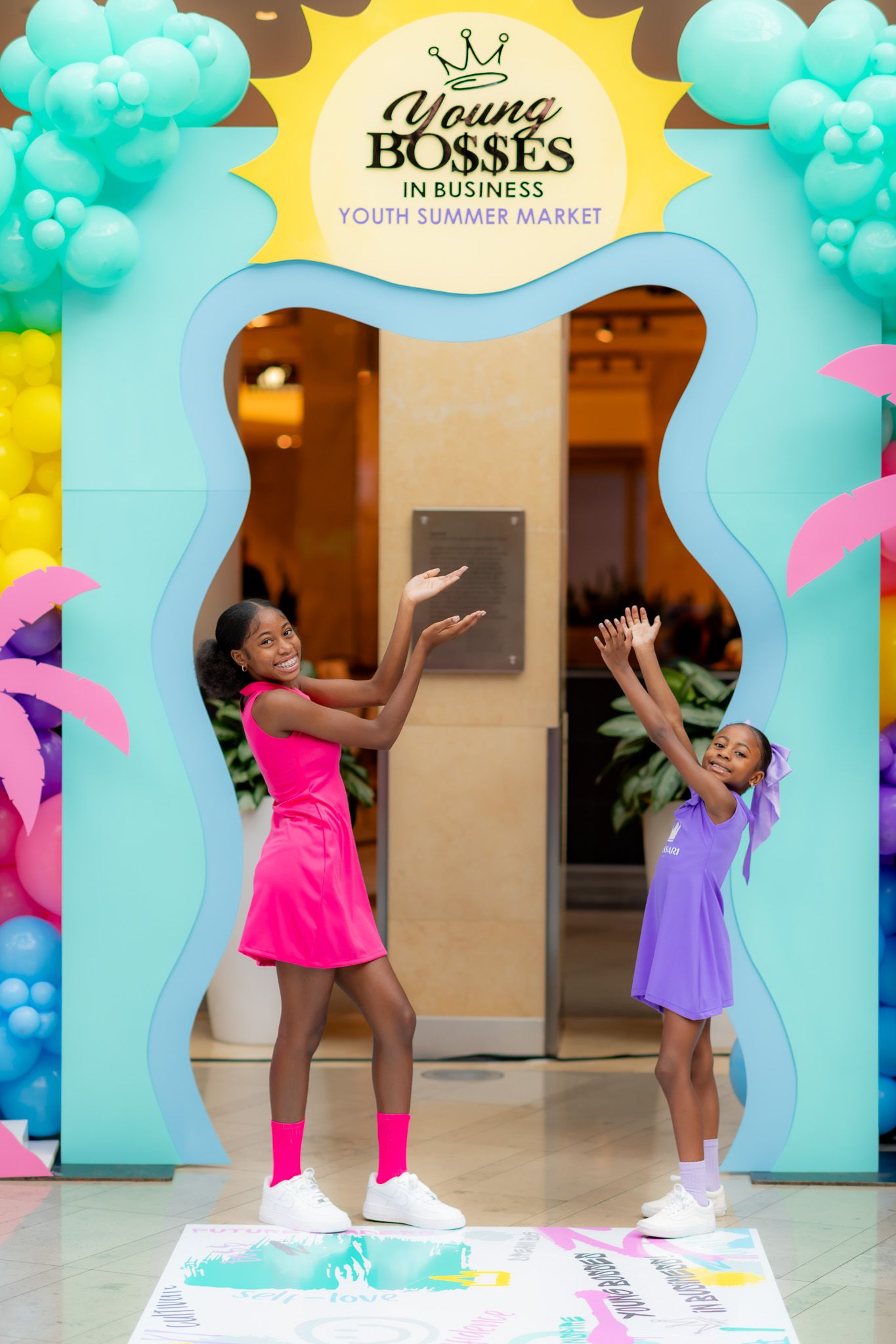 Colorful archway display with turquoise balloons and pink accents at a Young Bosses in Business youth market event.