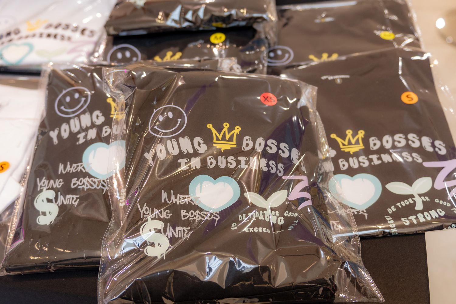 Black packaging bags with cute doodles and heart designs displayed for a youth business market event.