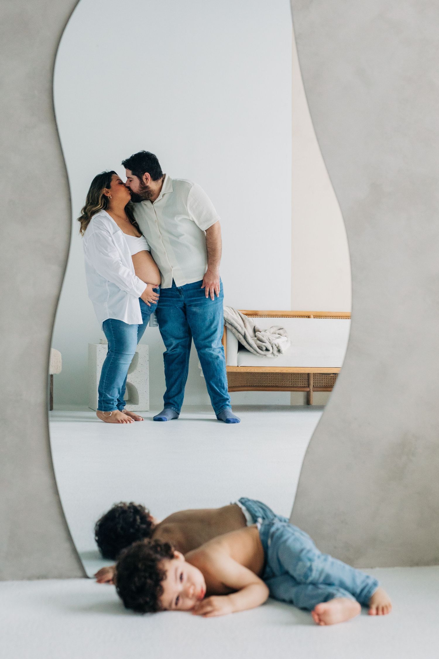 A creative family photo composition showing a couple embracing above while their child rests playfully below.
