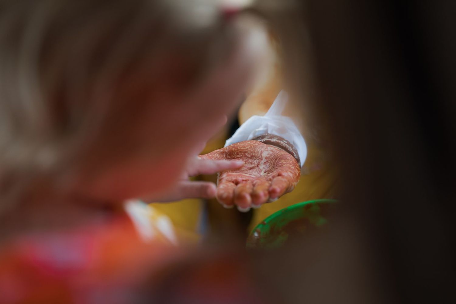Close-up of elderly hands covered in henna paste during an Indian wedding ceremony.