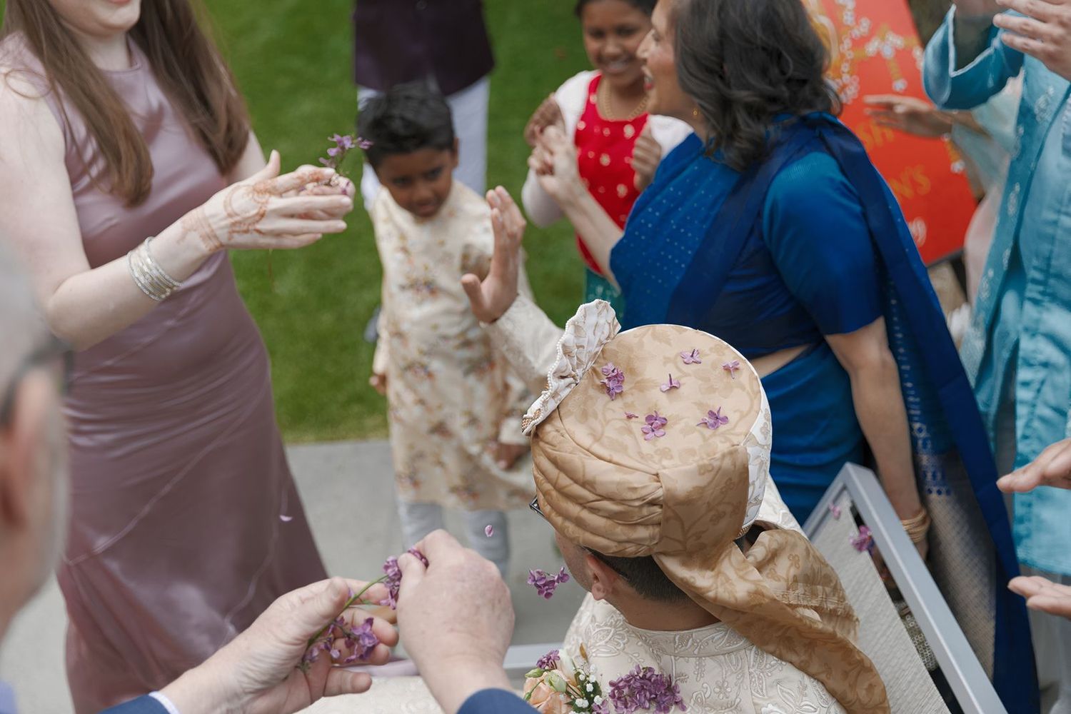 Wedding guests tossing flower petals over bride during traditional Indian wedding celebration outdoors.