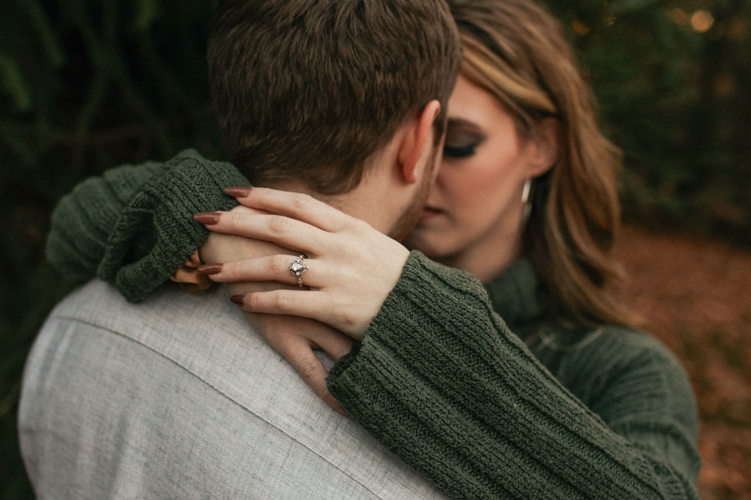 Romantic couple in autumn forest sharing intimate moment with soft natural lighting.