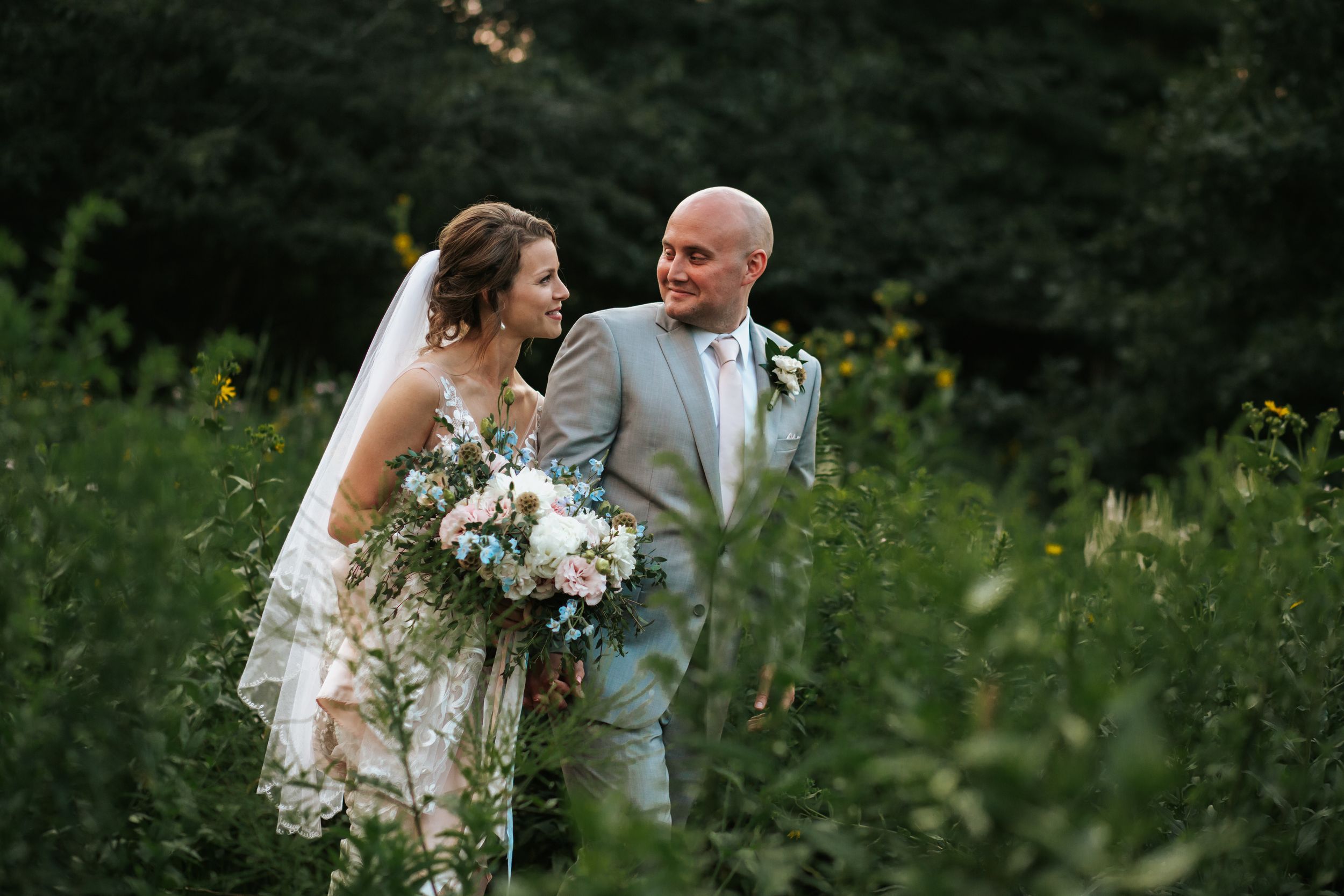 A couple shares a tender moment during their outdoor wedding ceremony in a lush garden setting.