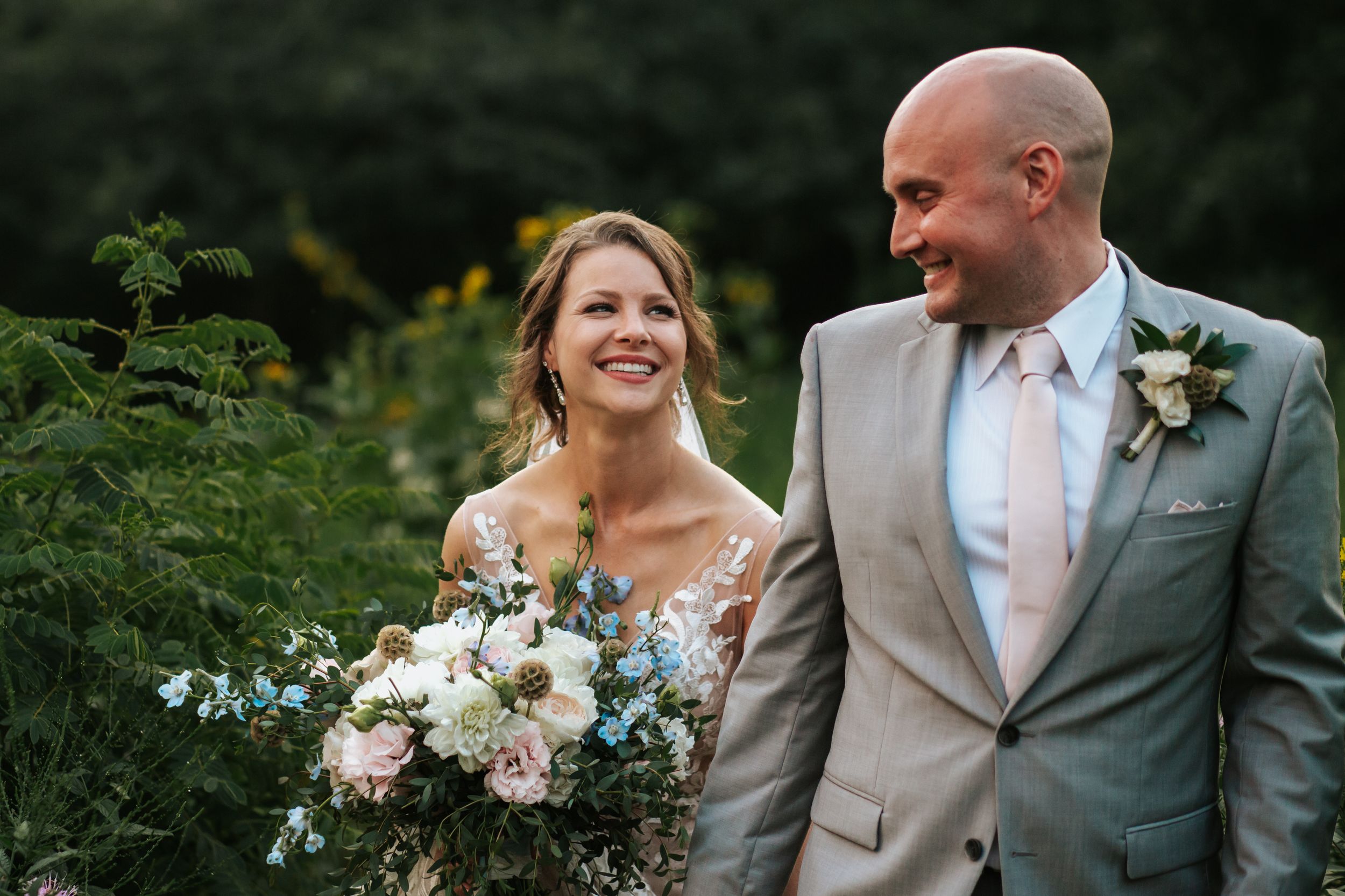 A romantic outdoor wedding photoshoot featuring a couple in formal attire with white floral bouquets.