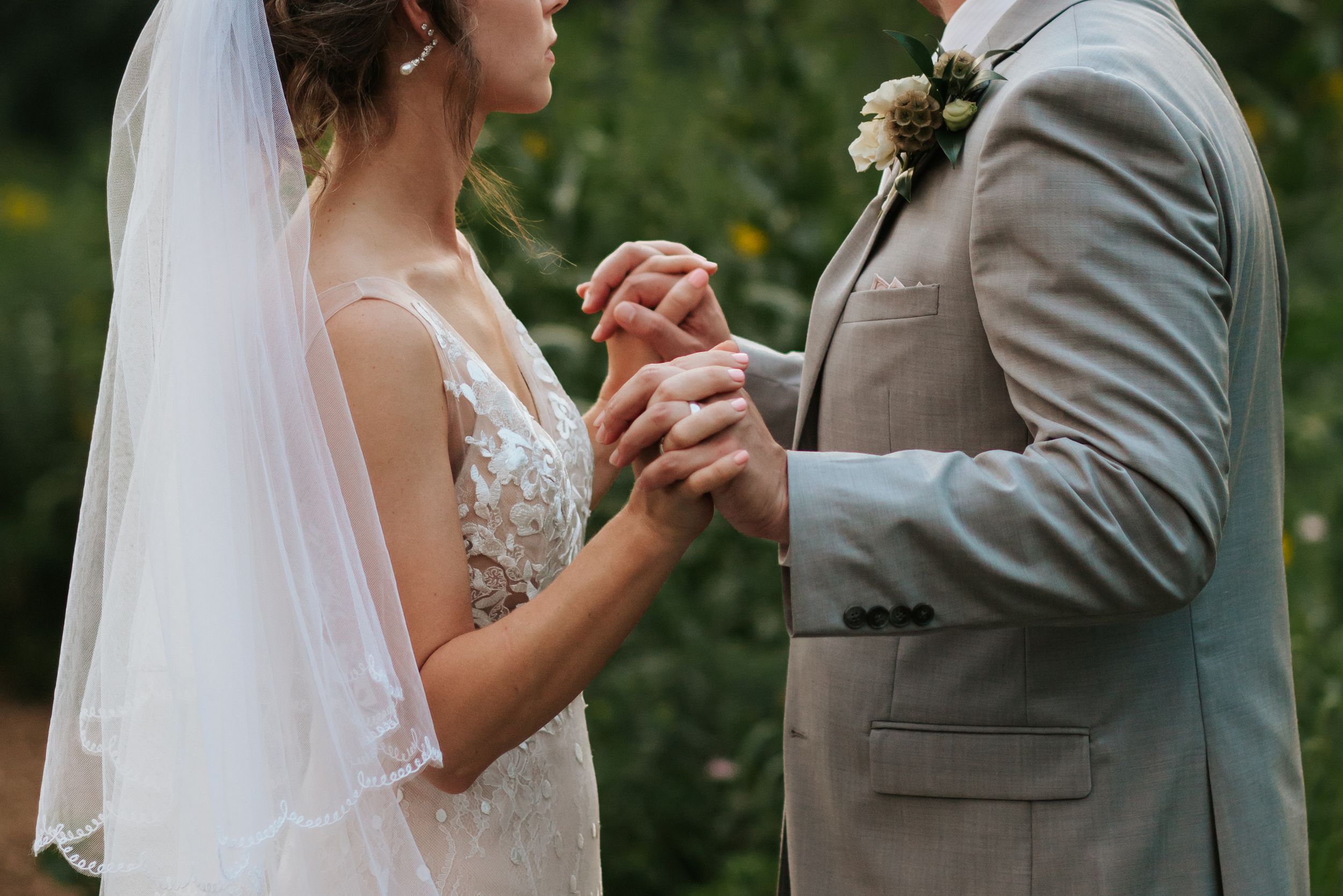 Couple dancing together during their wedding celebration in an outdoor garden setting with lush greenery.