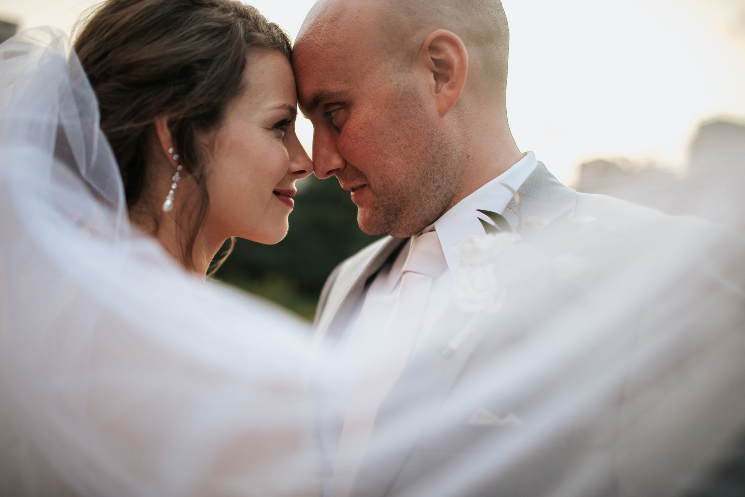 A tender moment between newlyweds as they share an intimate embrace under a flowing white veil.
