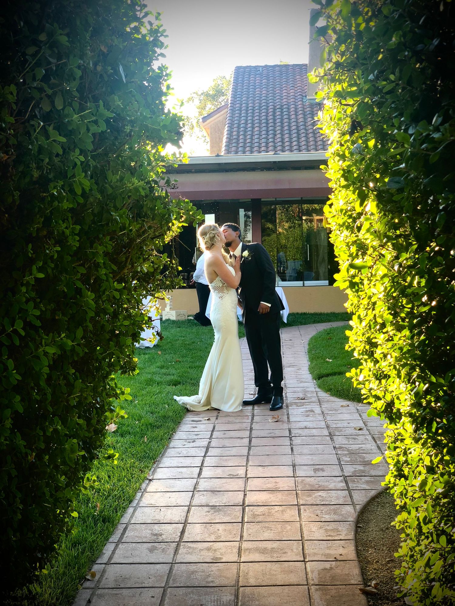 Garden wedding ceremony path lined with lush greenery and stone pavers.