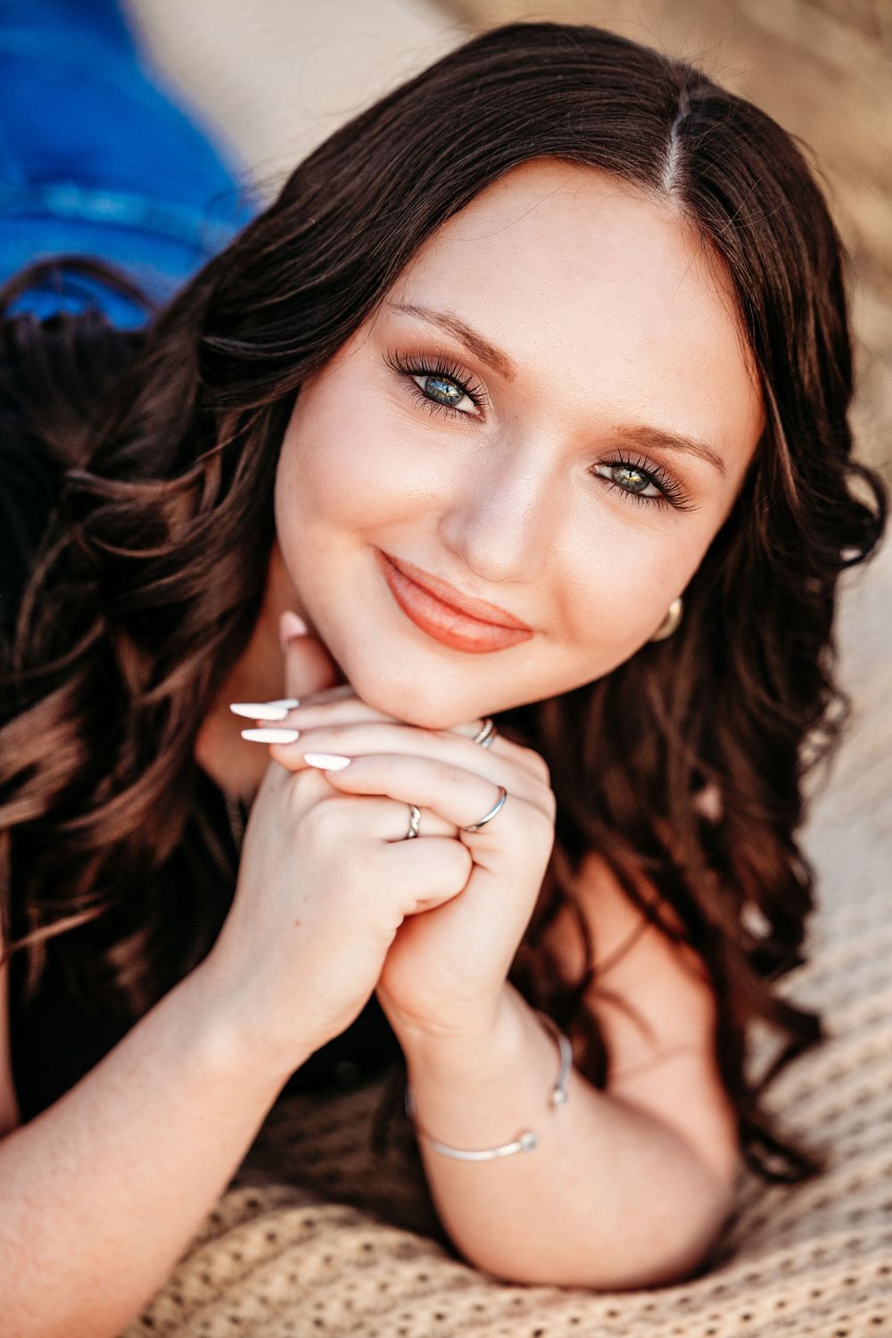 A senior girl in a black top and blue jeans poses outdoors during golden hour sunset in a natural setting in Fort Worth