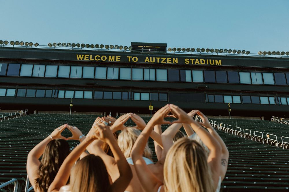 A panoramic view of empty bleachers and green field at Autzen Stadium with welcome signage visible.