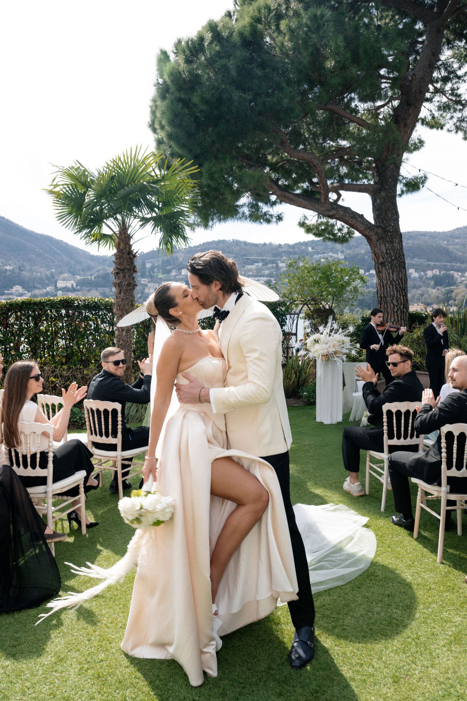 A joyful wedding ceremony moment on a scenic Mediterranean hillside with guests looking on.