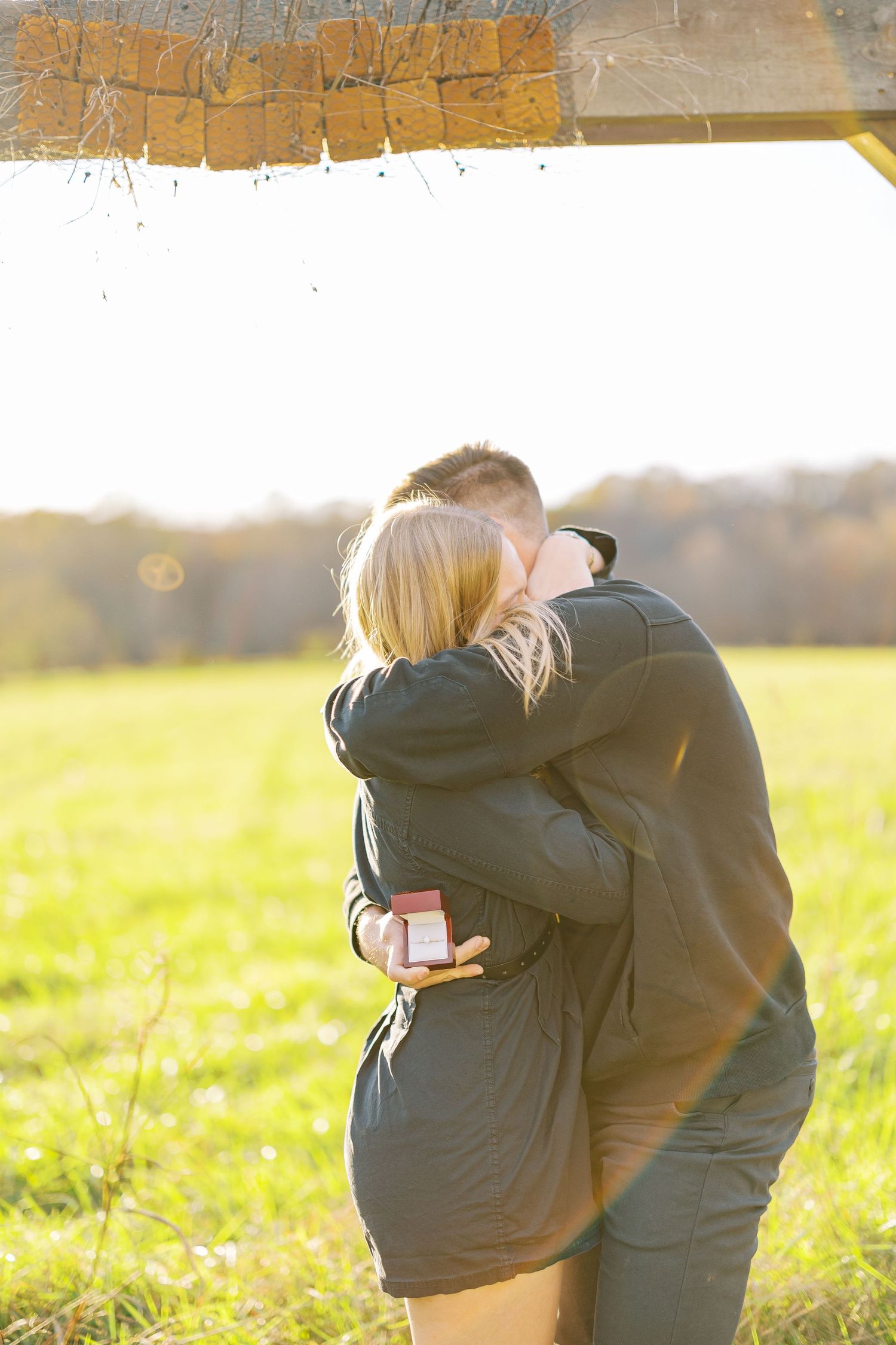 A couple in white and gray clothing share tender moments while sitting on autumn leaves in a park setting.