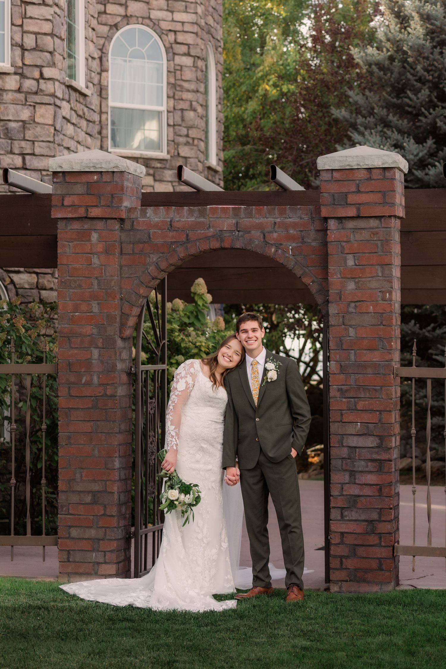 A romantic wedding portrait series showing a couple posing together in front of a brick archway and garden setting.