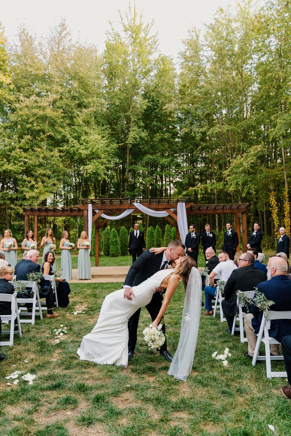 Wedding ceremony ending with the groom giving the bride a dip kiss in the aisle at The Venue On Lake Grant Mt Orab Ohio