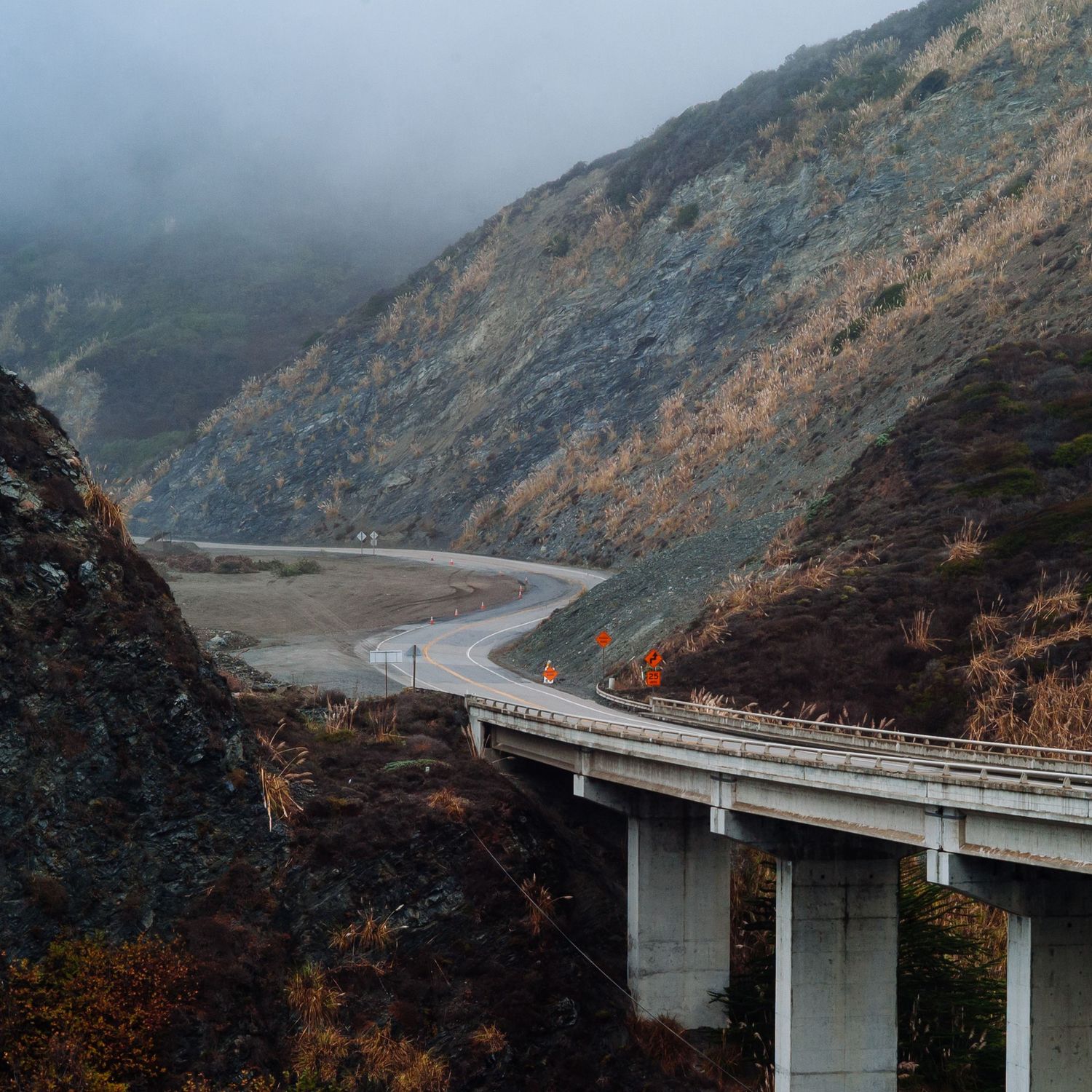 Elevated railway bridge curves through misty mountain landscape.