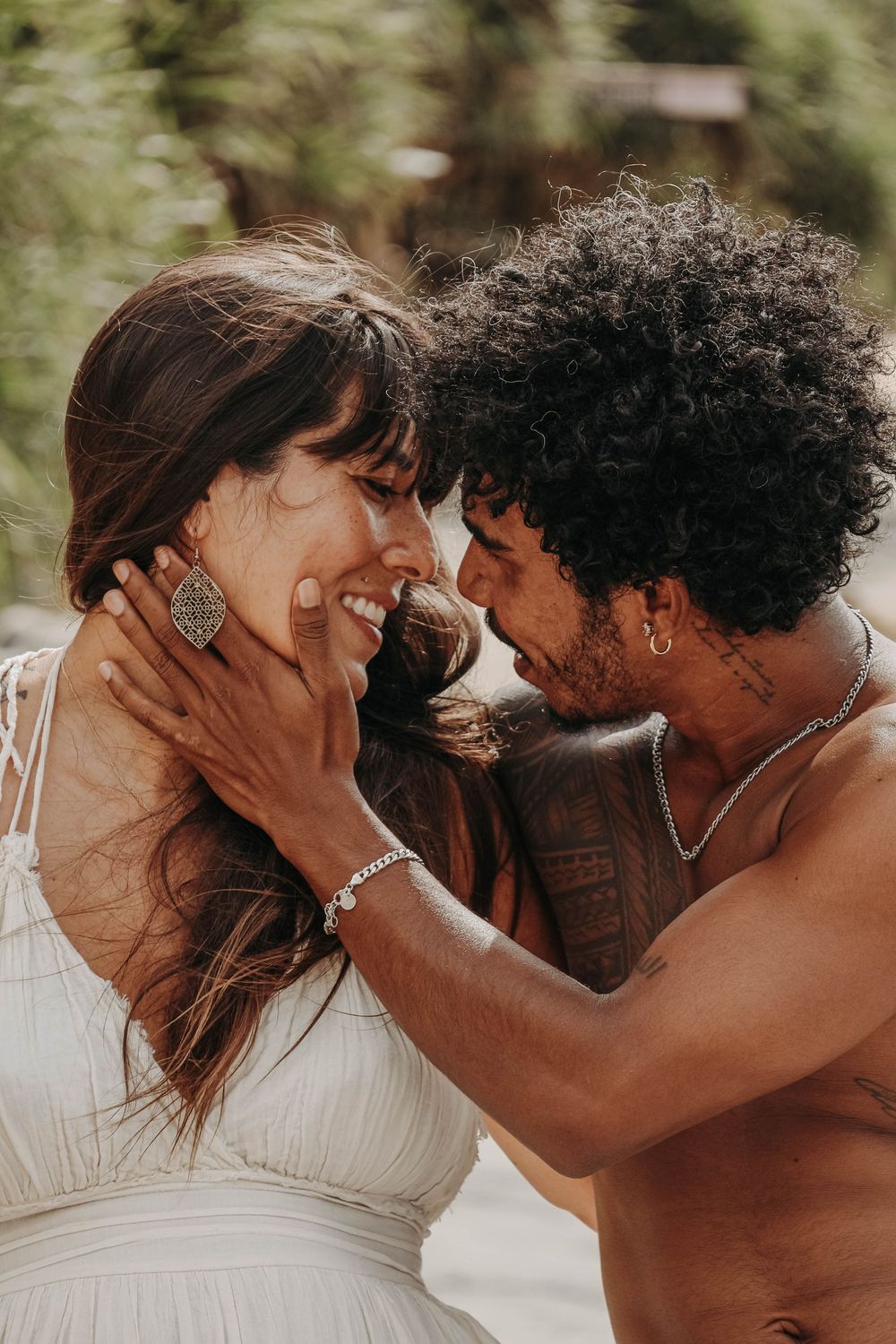 Joyful couple sharing an intimate moment outdoors, man gently cupping womans smiling face.
