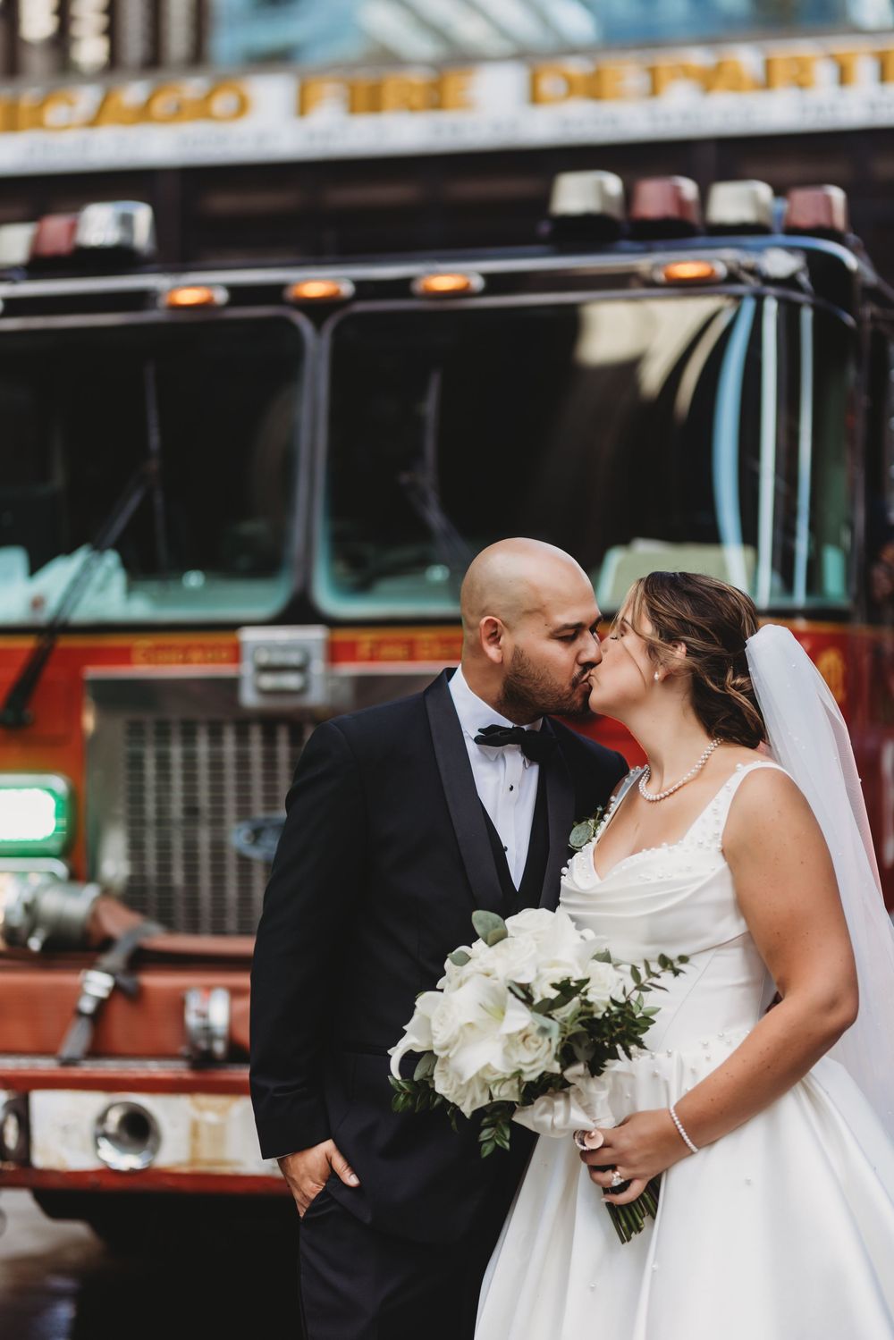 Wedding couple shares intimate moments in front of vintage fire trucks at their wedding celebration.