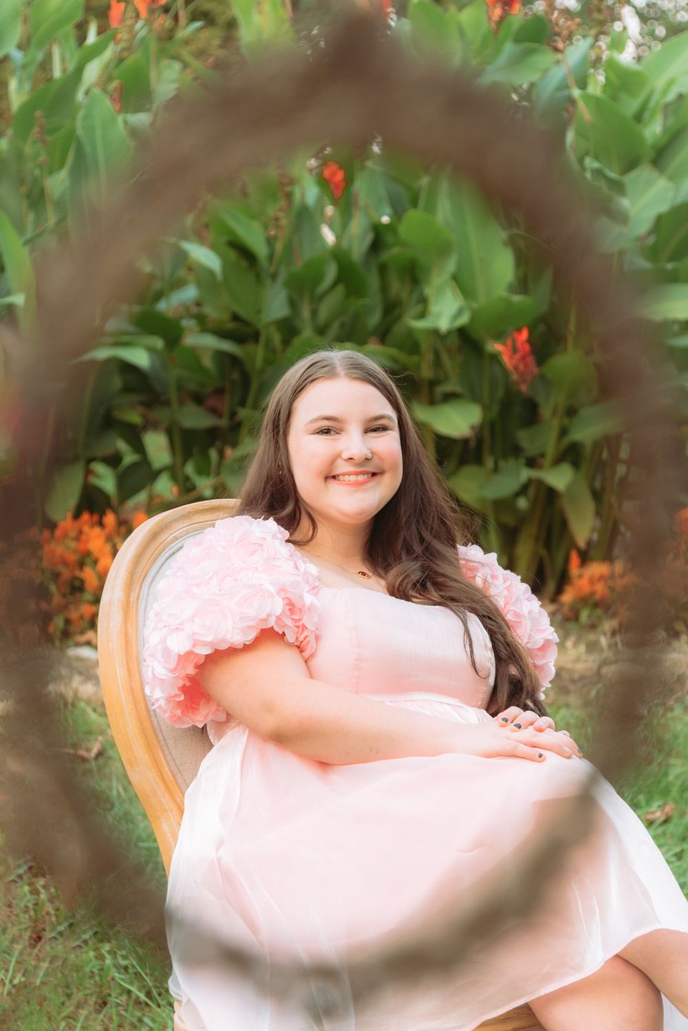 A pink dress stands out against vibrant orange flowers in an outdoor garden setting.