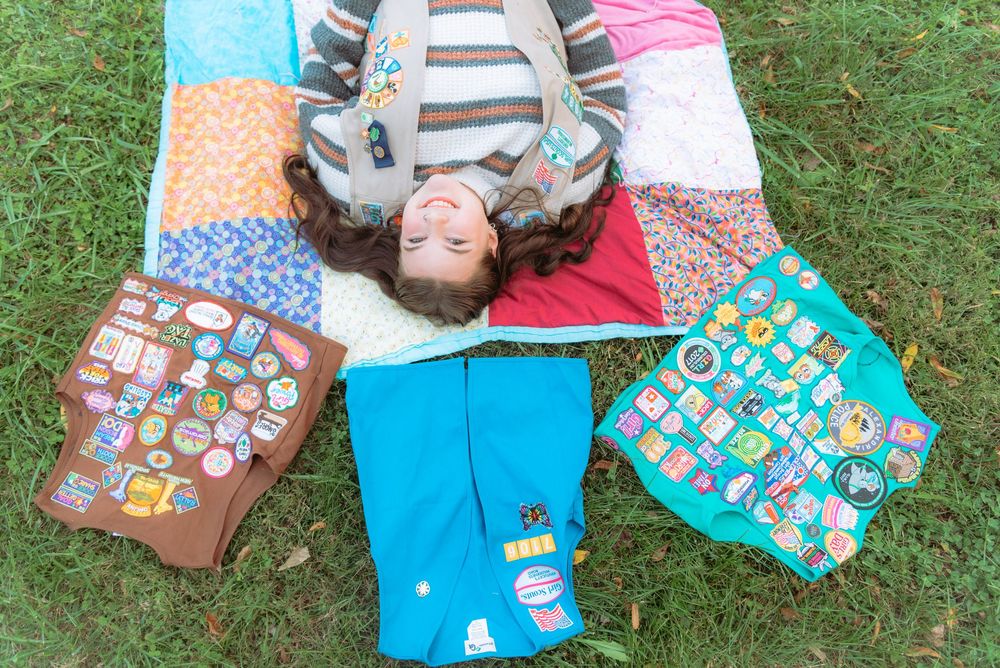 Graduates lying on grass with colorful blankets and pillows.
