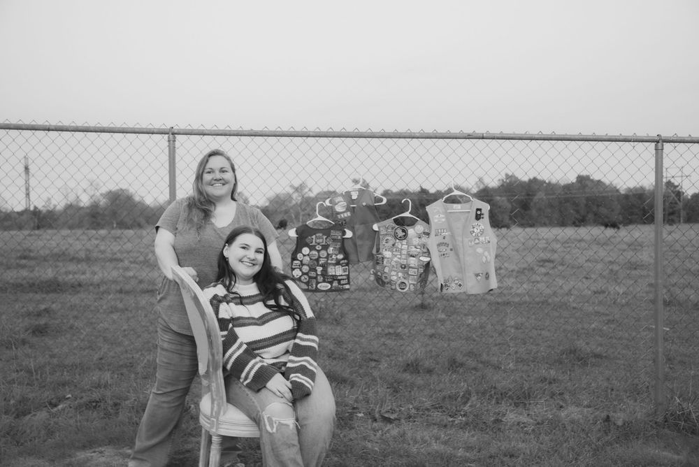Black and white photograph of graduates posing near a fence outdoors.