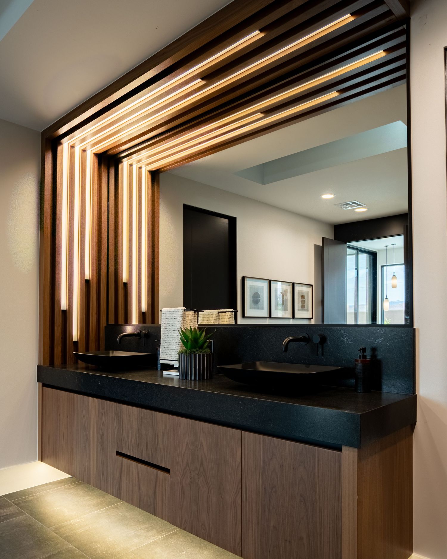 Modern office reception area with wooden slat wall feature and sleek black countertop under ambient lighting.