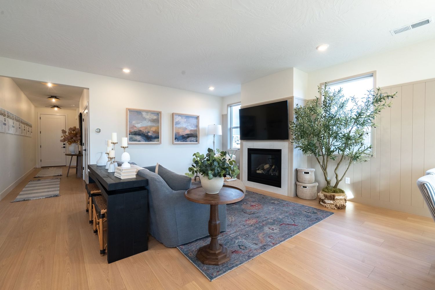 Modern open concept living space with recessed lighting, hardwood floors, and contemporary furnishings in a bright interior.