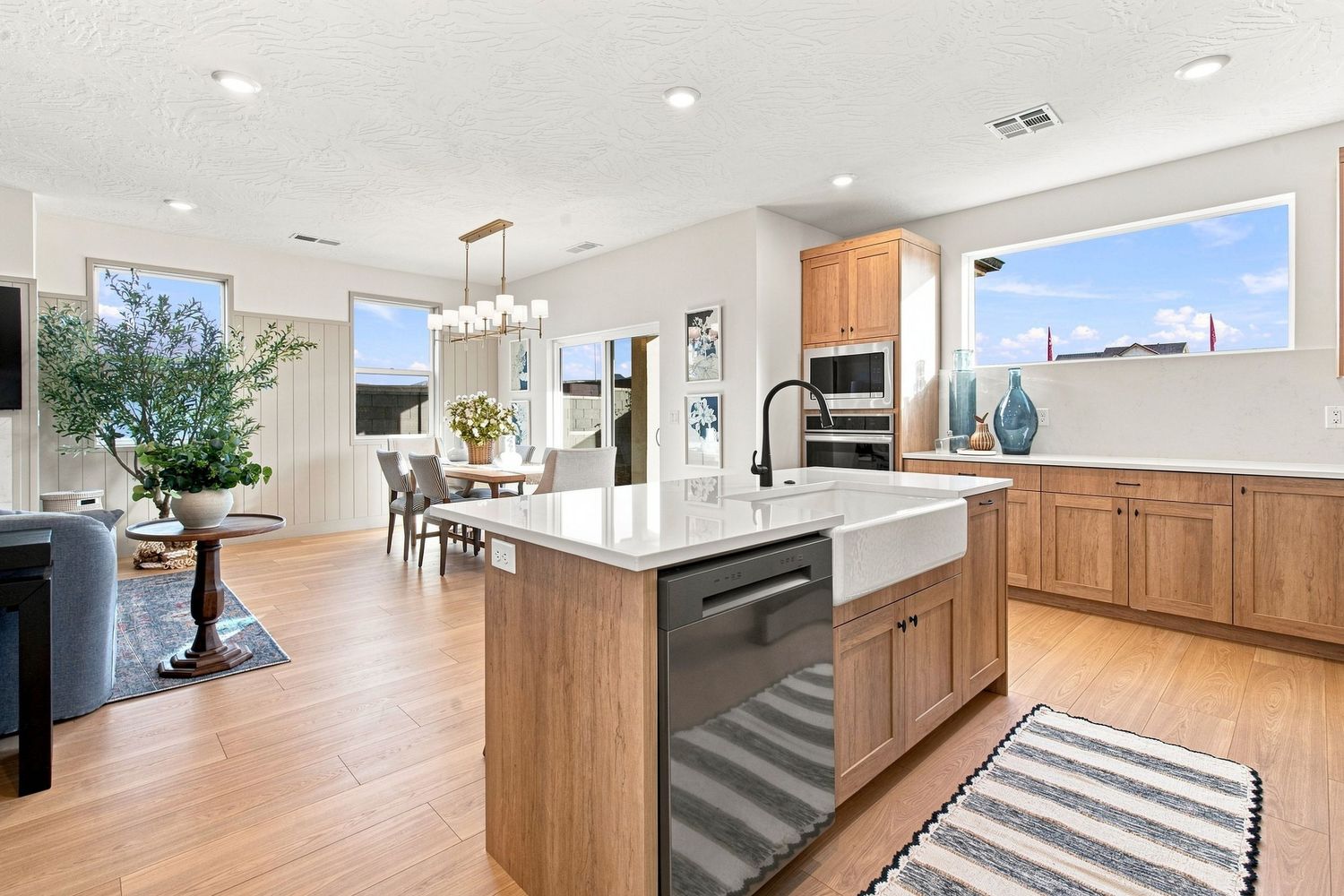 Modern kitchen with wood cabinets, island with wine fridge, white countertops, and open layout with dining area.