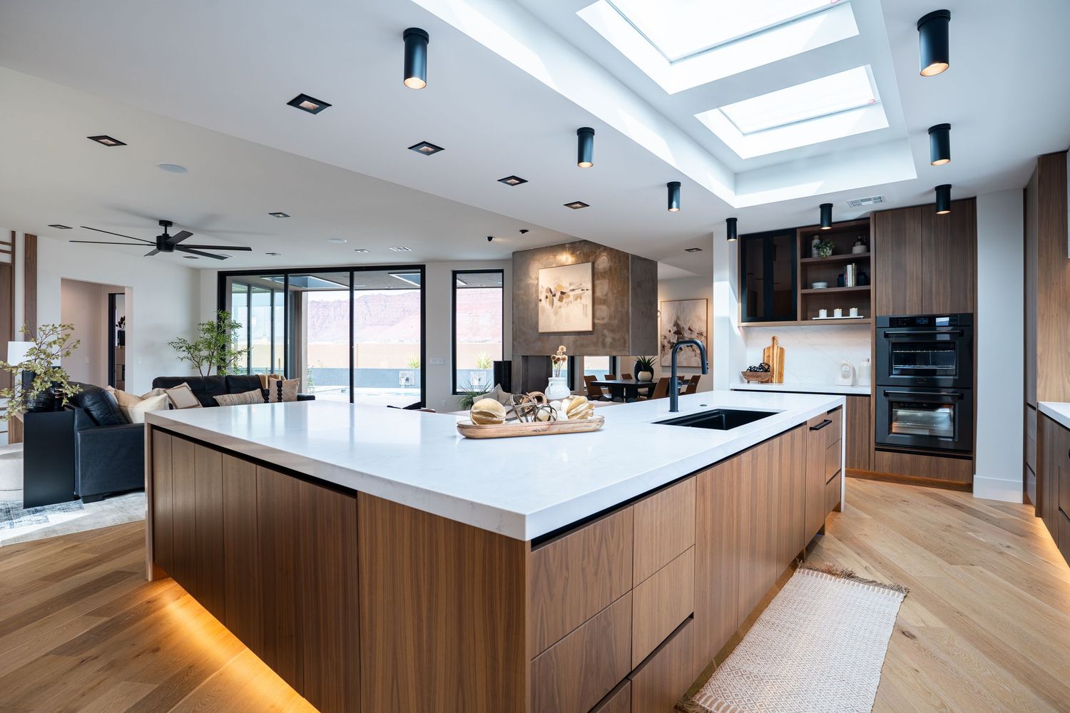 Modern open concept kitchen with wood paneling and skylights features sleek white countertops and minimalist design.