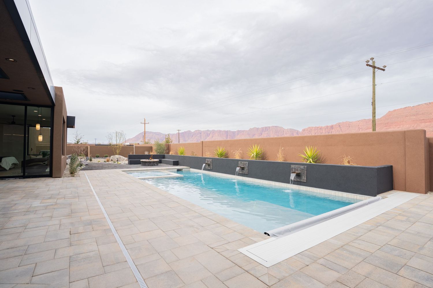 A modern swimming pool with stone tile decking and desert mountain views in the background creates a luxurious oasis setting.
