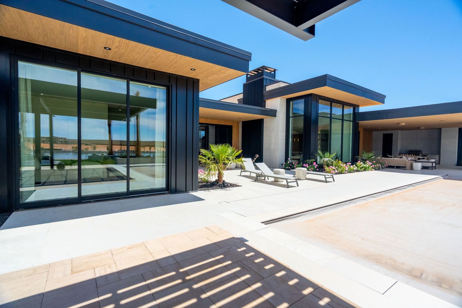 Modern luxury hillside home in St George,  with large glass windows, stone accents, and multiple outdoor terraces overlooking the landscape.