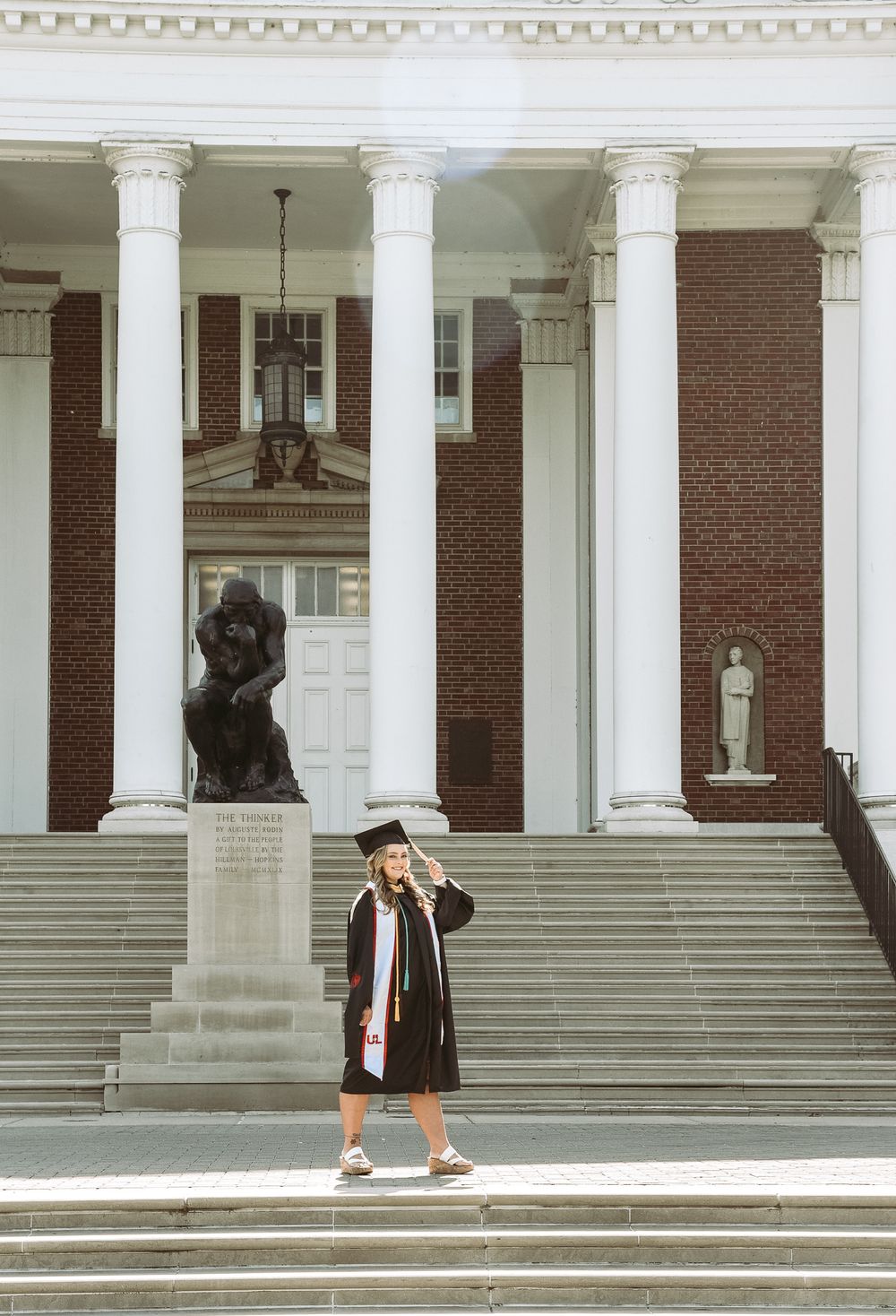 Classical brick building with white columns creates elegant graduation photo backdrop.