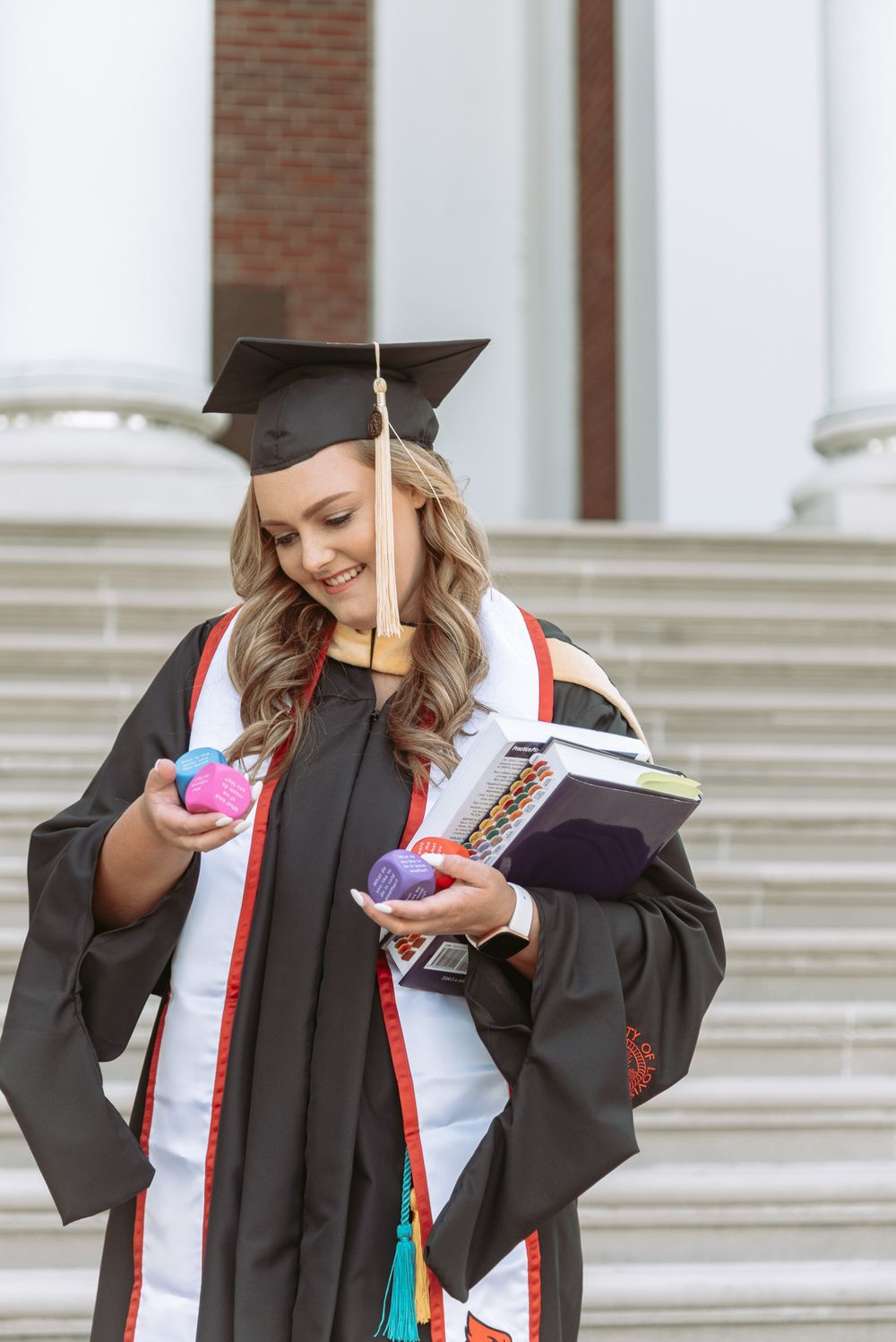 Graduate in black cap and gown holding diploma and smiling during graduation ceremony.