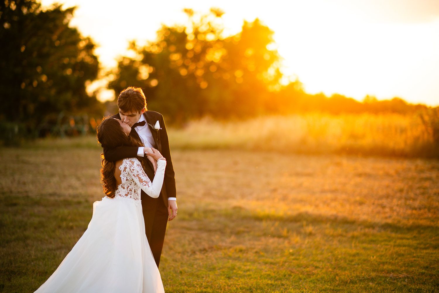 Bride and groom kissing in an open field during golden hour.Beautiful wedding venue in central Indiana